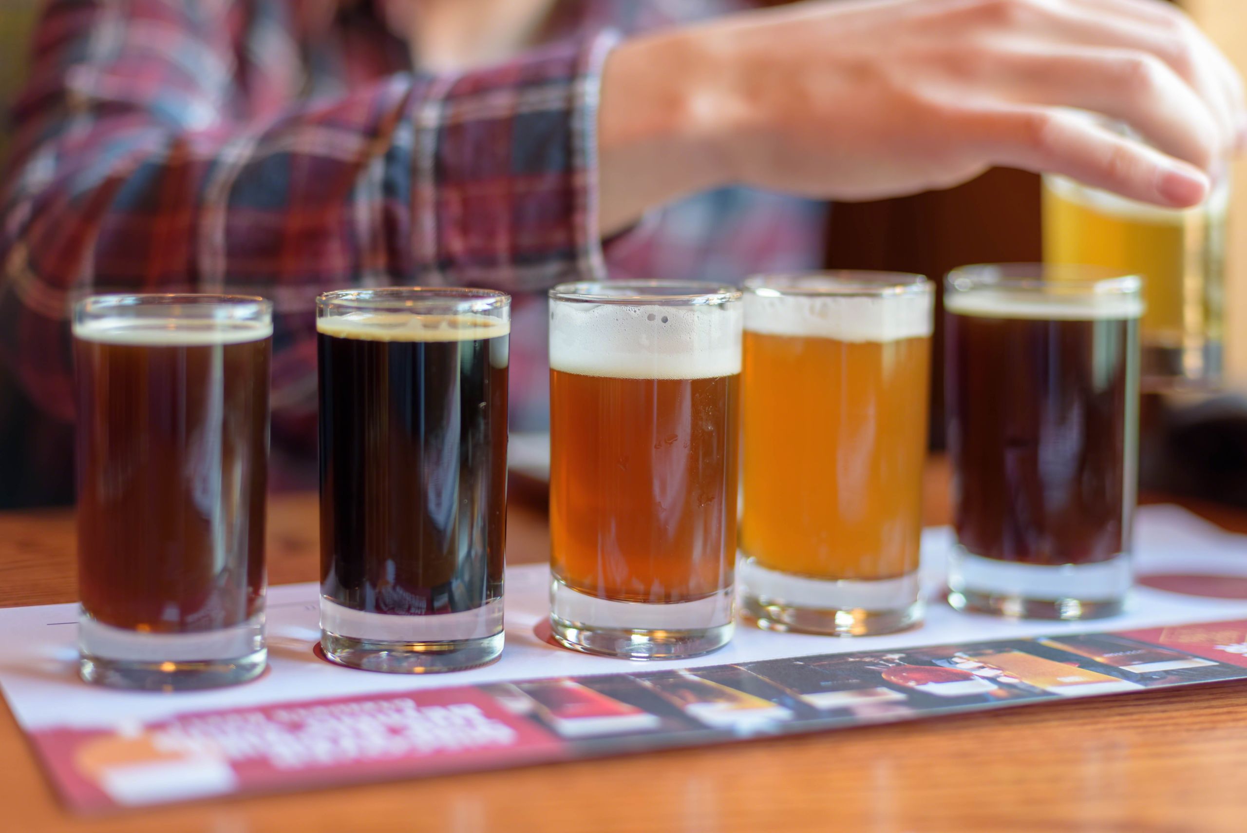 Young man tasting beer samples from a beer flight at a local brewery